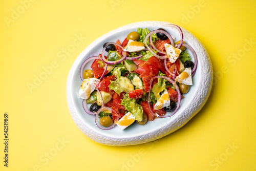 Greek salad in a plate on a yellow background