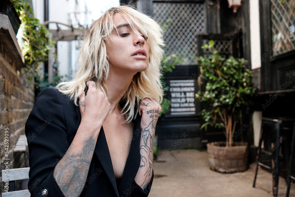 A young alternative model is posing sitting on a terrace pub. A young alternative model is posing sitting on a terrace pub.