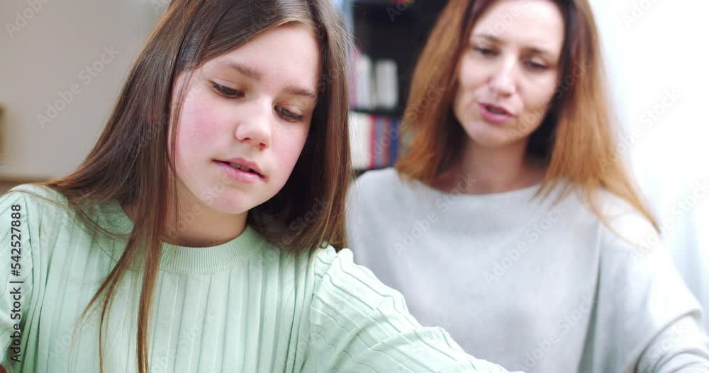 Close up of daughter and mother doing homework together. Cheerful glad mom and kid. Happy student girl learning online with tablet. Technologies for studying. Elementary school concept. Close up of daughter and mother doing homework together. Cheerful glad mom and kid. Happy student girl learning online with tablet. Technologies for studying. Elementary school concept.
