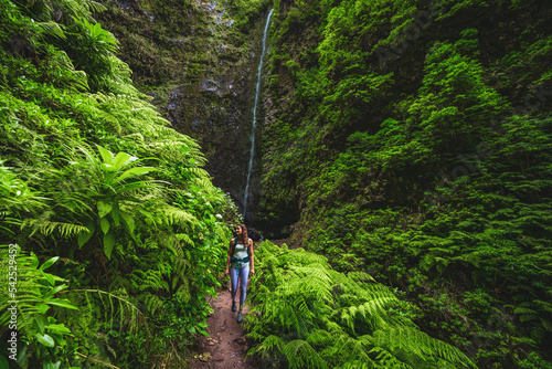 Beautiful athletic woman walks along flowery and farny trail at amazing jungle water fall. Levada of Caldeir  o Verde  Madeira Island  Portugal  Europe.