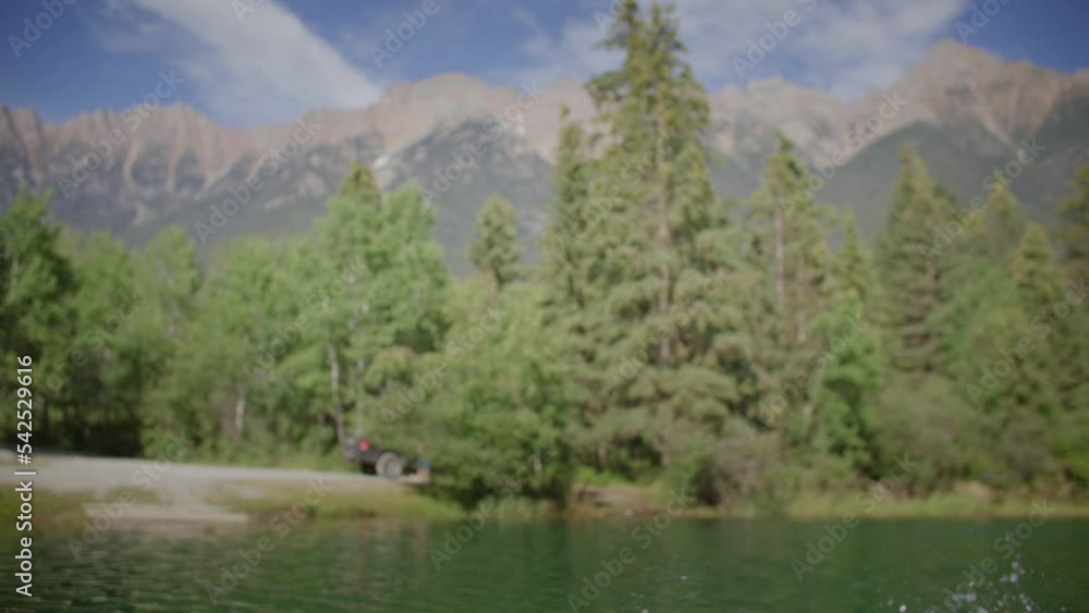 Carefree man dives off dock into lake, mountain backdrop Carefree man dives off dock into lake, mountain backdrop
