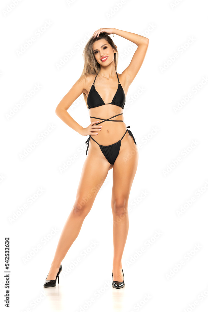 Pretty young smiling woman posing in black swimsuit on white background. Front view. Pretty young smiling woman posing in black swimsuit on white background. Front view.