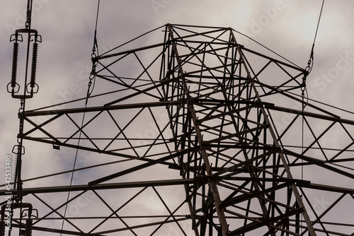 Duży elektryczny ,  słup stalowy o ażurowej konstrukcji na tle szarego nieba . photo