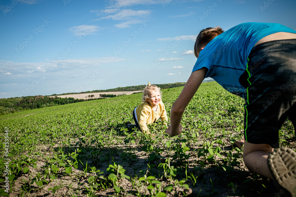 A boy and a girl have fun crawling across the field in the spring. Children play in nature. Lifestyle A boy and a girl have fun crawling across the field in the spring. Children play in nature. Lifestyle