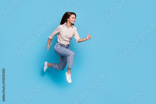 Full size profile photo of positive energetic lady run jump good mood hurry blach friday shopping sale isolated on blue color background photo