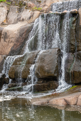 Finland, Kotka - July 18, 2022: Sopokanlahti park and lake. Closeup of waterfall base showing flows of white water over brown wet rocks