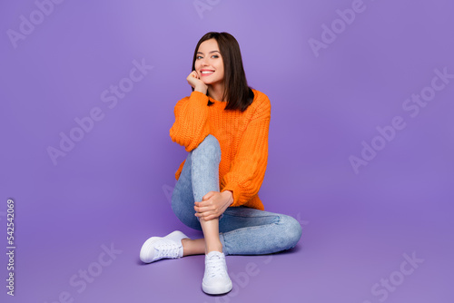 Full length photo of stunning young lady sitting floor shopping dressed stylish knitted orange garment isolated on purple color background © deagreez