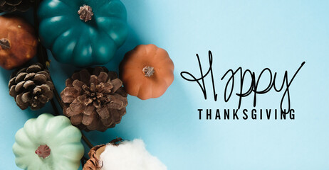 Top view of pumpkins and pinecones on blue thanksgiving background for holiday card.