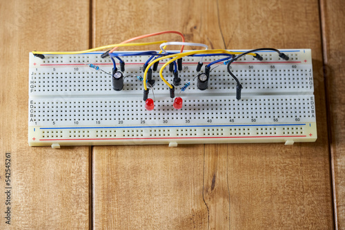 Breadboard with electrical elements, on a wooden table. photo