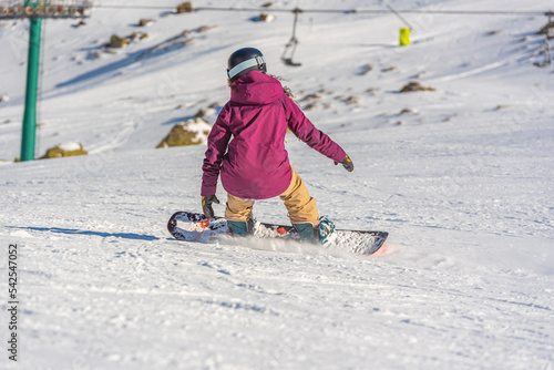 Young woman snowboarder in motion on snowboard in mountains