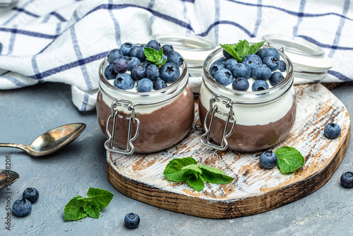 Delicious chocolate mousse or pudding with whipped cream. Chocolate panna cotta with blueberries. Chocolate pudding and greek yogurt parfait