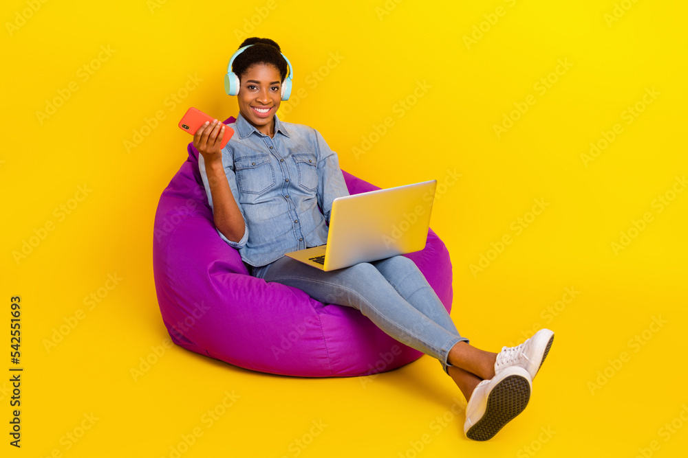 Full body portrait of positive person sit purple bag hold telephone wireless netbook isolated on yellow color background Full body portrait of positive person sit purple bag hold telephone wireless netbook isolated on yellow color background