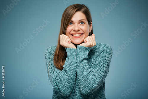 Excited young woman in blue warm clothes leaned on her hands and looking up. isolated studio portrait.