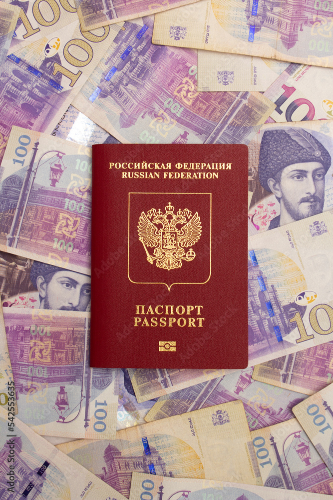Vertical photo of Russian biometric passport on paper Georgian cash banknotes. Banknote 100 lari. The concept of moving to Georgia. Travel and tourism. Relocation due to the war in Ukraine. GEL