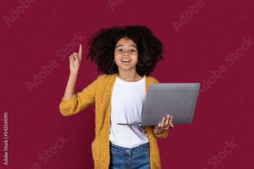 Smart black girl using laptop, showing eureka gesture