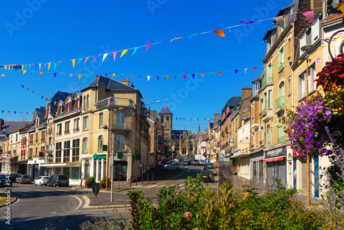 Summer view of Rethel cityscape during Feast of Assumption overlooking streets decorated with festive garland of small colorful triangular flags and Saint-Nicolas Church in background, France. photo