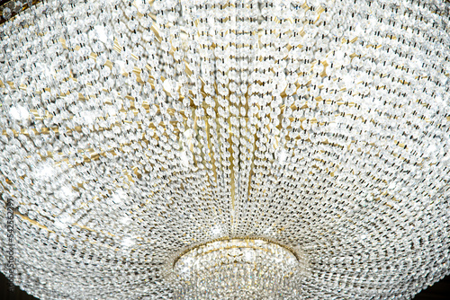 large round chandelier with crystals and candlesticks on the ceiling, dark background, retro style. Beautiful chandelier in luxury room shining.