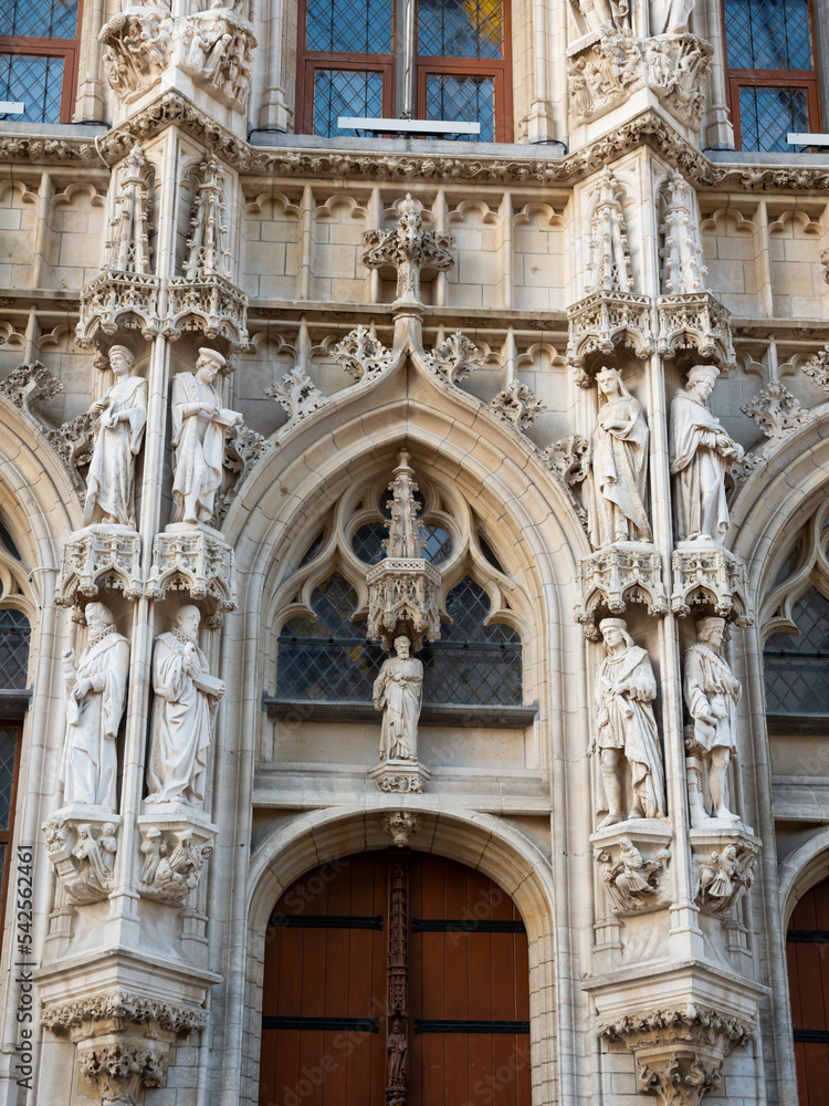 Closeup of lace-like sculptural details and statues on facade of gothic Leuven Town Hall building. Famous Belgian landmark