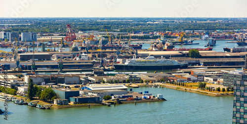 Aerial view of Rotterdam seaport territory overlooking docks and harbour-basins with cargo cranes and loading barges on sunny summer day, Netherlands
