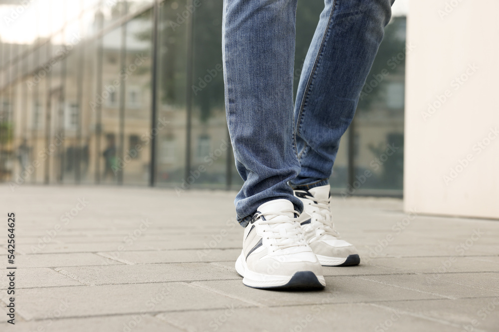 Man in jeans and sneakers walking on city street, closeup. Space for text Man in jeans and sneakers walking on city street, closeup. Space for text