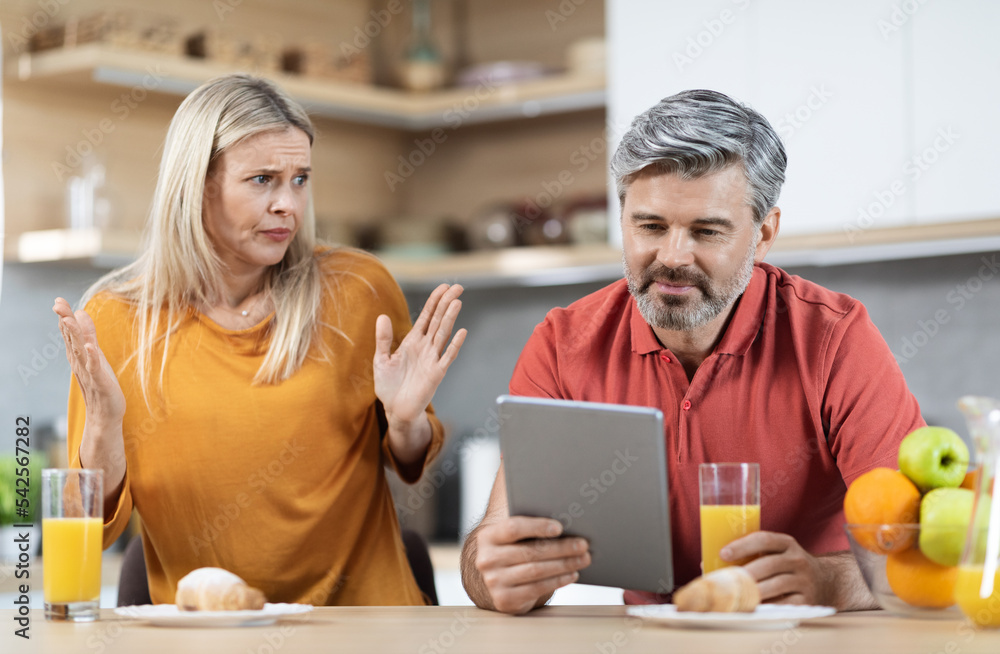 Angry wife fighting with her husband using digital tablet Angry wife fighting with her husband using digital tablet