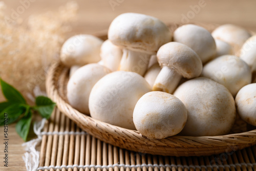 Fresh white champignon mushroom in basket on wooden background