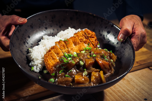 Japanese chicken katsu curry rice, deep fried breast chicken fillet with beef, carrot and potato curry in black plate on wooden table Crispy fried pork cutlet with curry rice - Japanese food style