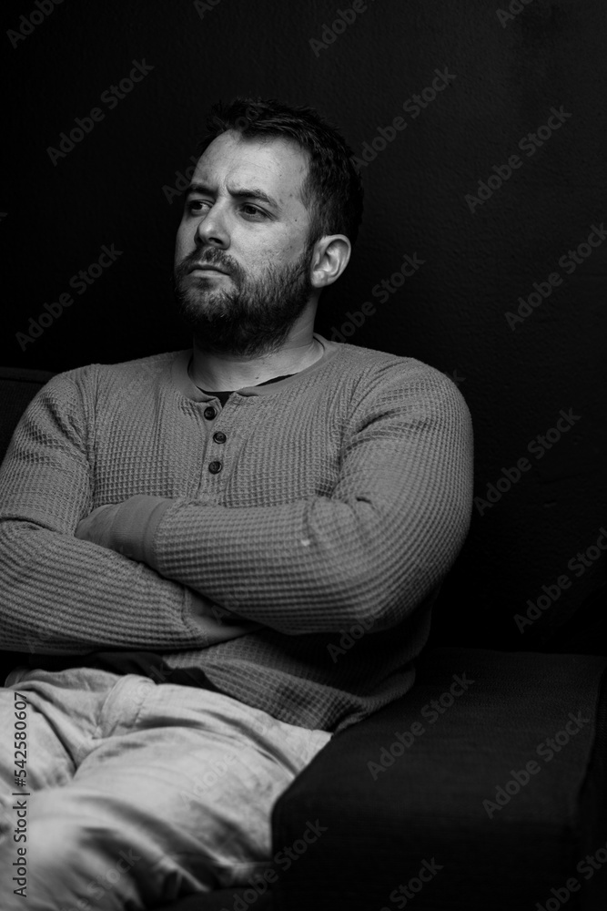 Indoor portrait of young european caucasian man thinking isolated seated in a sofa. High Fashion male model Indoor portrait of young european caucasian man thinking isolated seated in a sofa. High Fashion male model