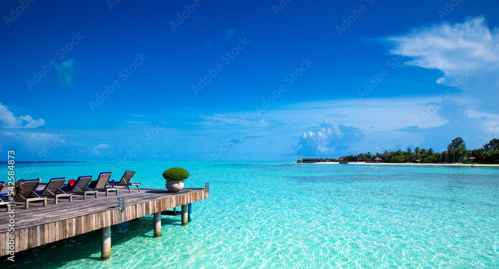 tropical beach in Maldives with few palm trees and blue lagoon.
