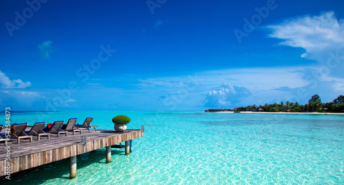 tropical beach in Maldives with few palm trees and blue lagoon.