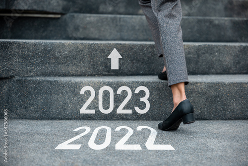 Happy new year 2023. Stepping going up stairs in city, Closeup legs of businesswoman hurry up walking on stairway from 2022 to 2023, foot of business woman wear black shoes step up success next years