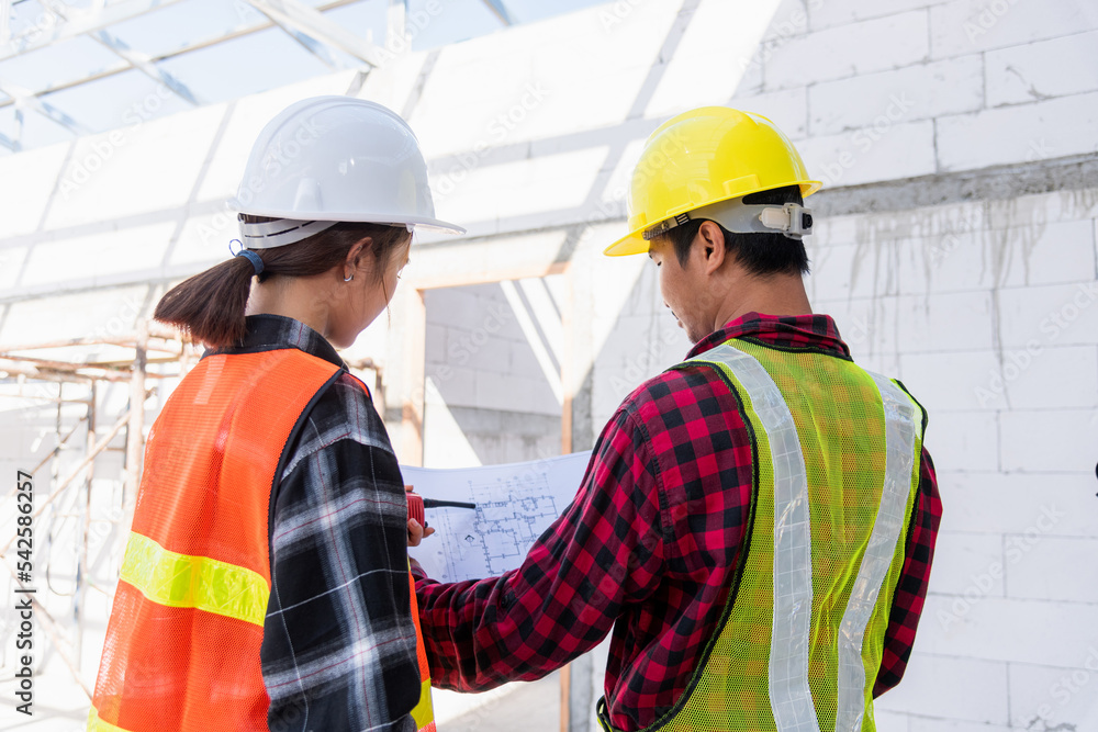 Architect and client discussing the plan with blueprint of the building at construction site. Asian engineer foreman worker man and woman working talking on drawing paper to checking project Architect and client discussing the plan with blueprint of the building at construction site. Asian engineer foreman worker man and woman working talking on drawing paper to checking project