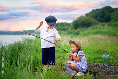Two kids are fishing by the water. A boy and a girl with a fishing rod catch everything from the lake.