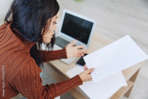 A sad freelance woman with a laptop on her desk works online from home shrugs her hands in incomprehension