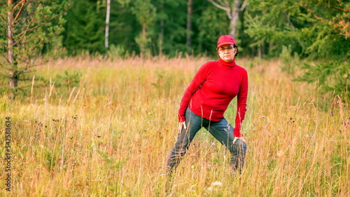 beautiful mature women doing gymnastics in a clearing in a coniferous forest on a summer day