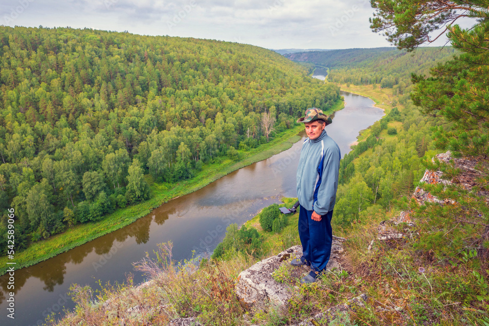 young male Tourist On a high rocky bank of the river meets Dawn on a summer day young male Tourist On a high rocky bank of the river meets Dawn on a summer day