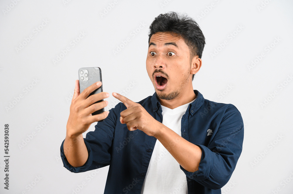 Protrait of Young asian man expressing surprise while using mobile phone isolated over white background Protrait of Young asian man expressing surprise while using mobile phone isolated over white background