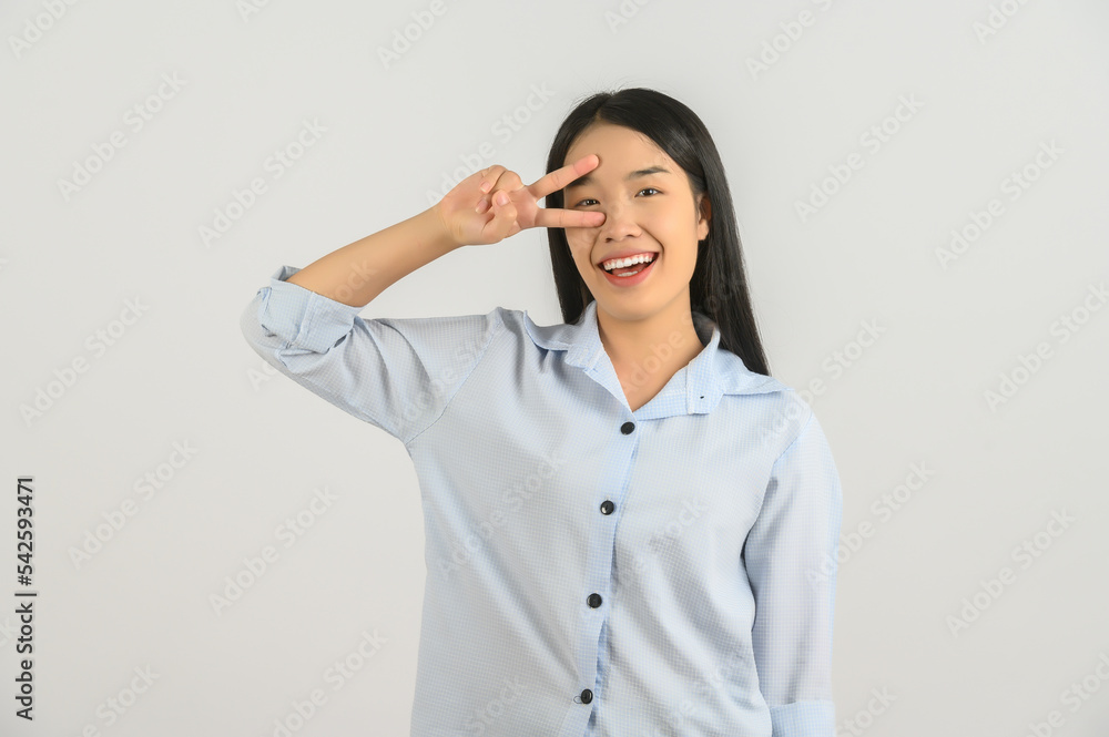 Portrait of Happy young asian woman in blue shirt doing peace symbol with fingers over face isolated on white background Portrait of Happy young asian woman in blue shirt doing peace symbol with fingers over face isolated on white background
