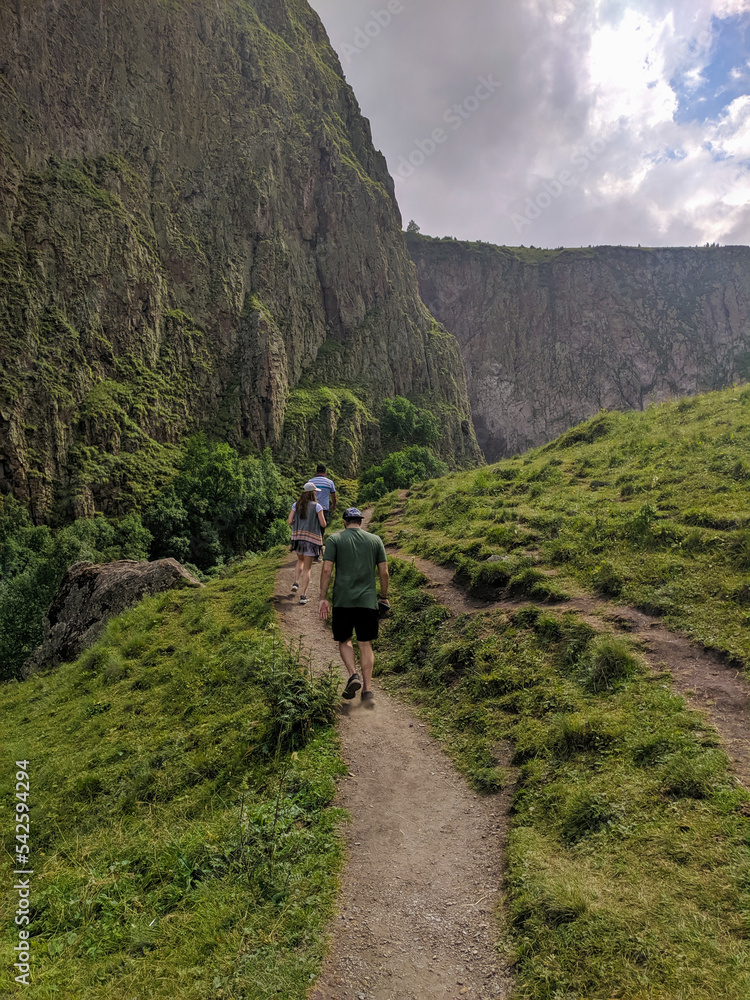 Obraz premium View of the Caucasian mountains in the Jily-su valley. People walk up the path to the mountains. Vertical. Prielbrusye National Park, Kabardino-Balkaria, Caucasus, Russia