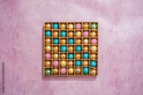 cardboard box with many christmas spheres  with pink background