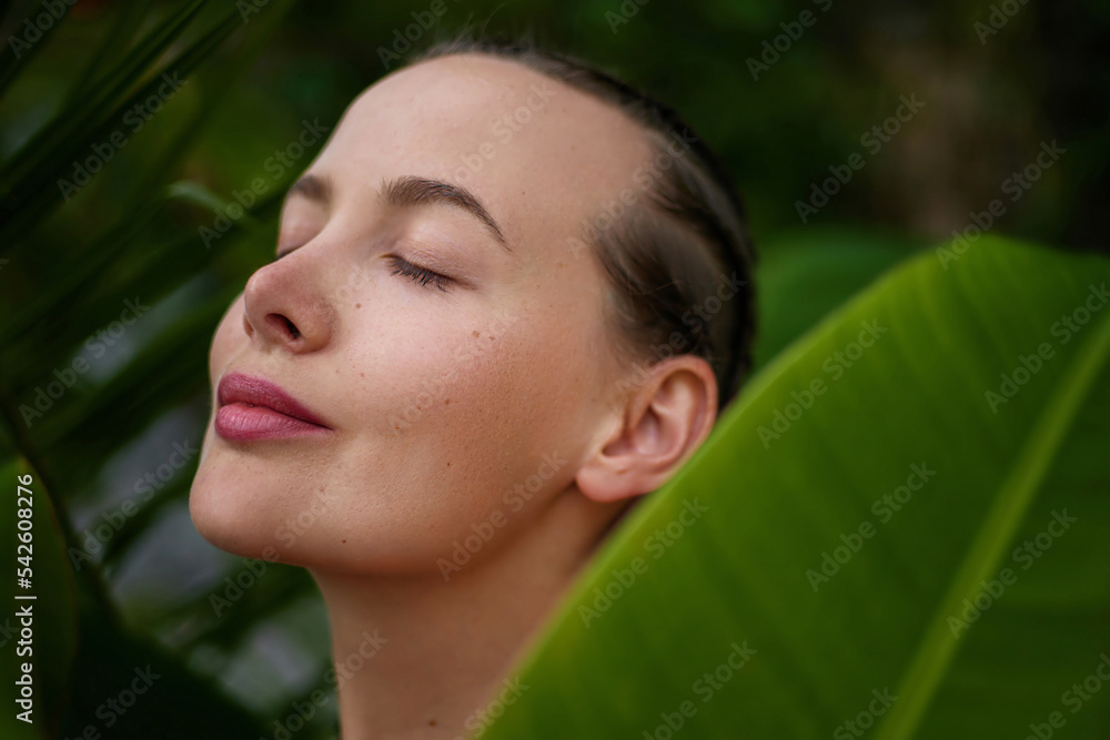 Green beauty portrait. Beautiful young woman posing against and behind fresh green tropical banana leaves. Green beauty portrait. Beautiful young woman posing against and behind fresh green tropical banana leaves.