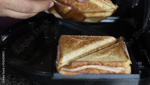 taking 2 toasted whole wheat sandwiches out of the sandwich maker