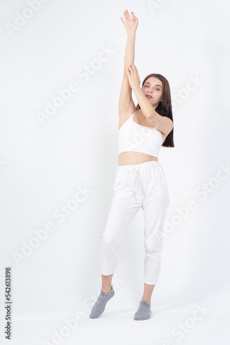 The girl is dressed for summer in a white top and knitted trousers. She is posing in the studio on a white background. © Михаил Таратонов