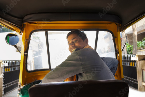 Portrait of a happy auto rickshaw driver looking back photo