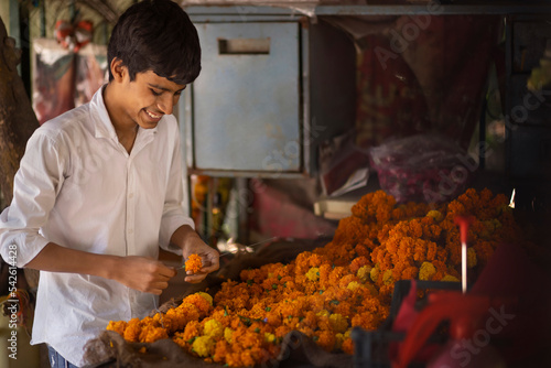 Happy boy making flower garland in flower shop photo