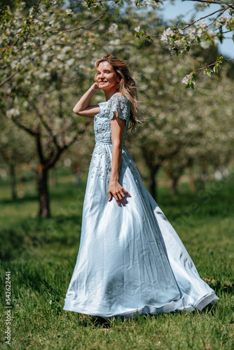 Portrait of a blonde in the park. Beautiful woman with long blond hair in a blue dress.