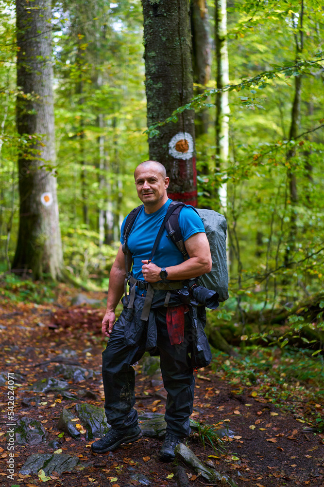 Photographer with heavy backpack and camera in the forest Photographer with heavy backpack and camera in the forest