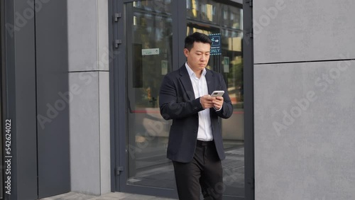 Wallpaper Mural Asian businessman leaves office building, working on mobile phone while going to other place, manager in business clothes goes home after work. Korean businessman typing message outdoor, using phone. Torontodigital.ca