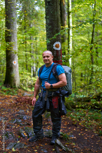 Photographer with heavy backpack and camera in the forest