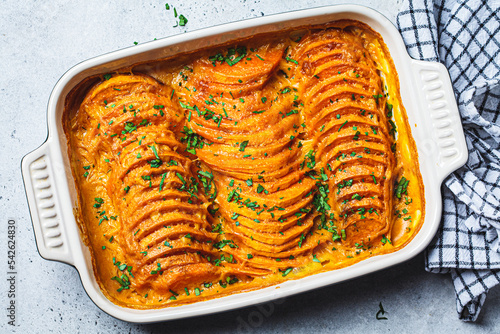 Roasted sweet potato gratin with parsley in ceramic pan. Vegan healthy recipe concept.